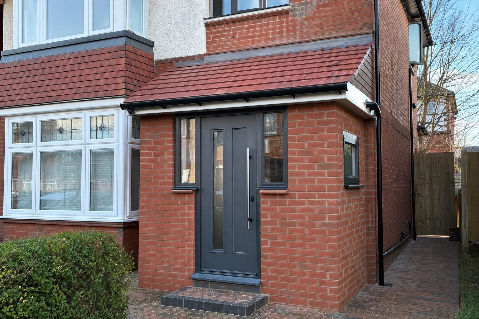 New brick porch with a pitched tiled roof and anthracite composite door on a 1930s semi