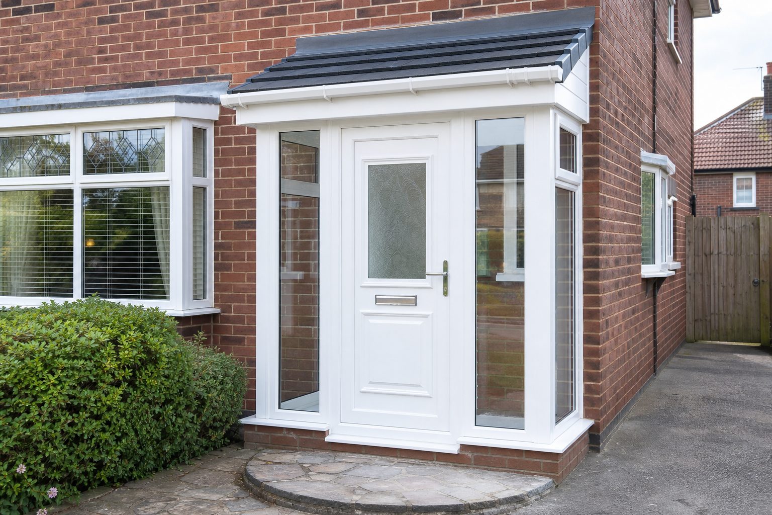 New white uPVC porch with glazed panels and a white uPVC door on a brick house